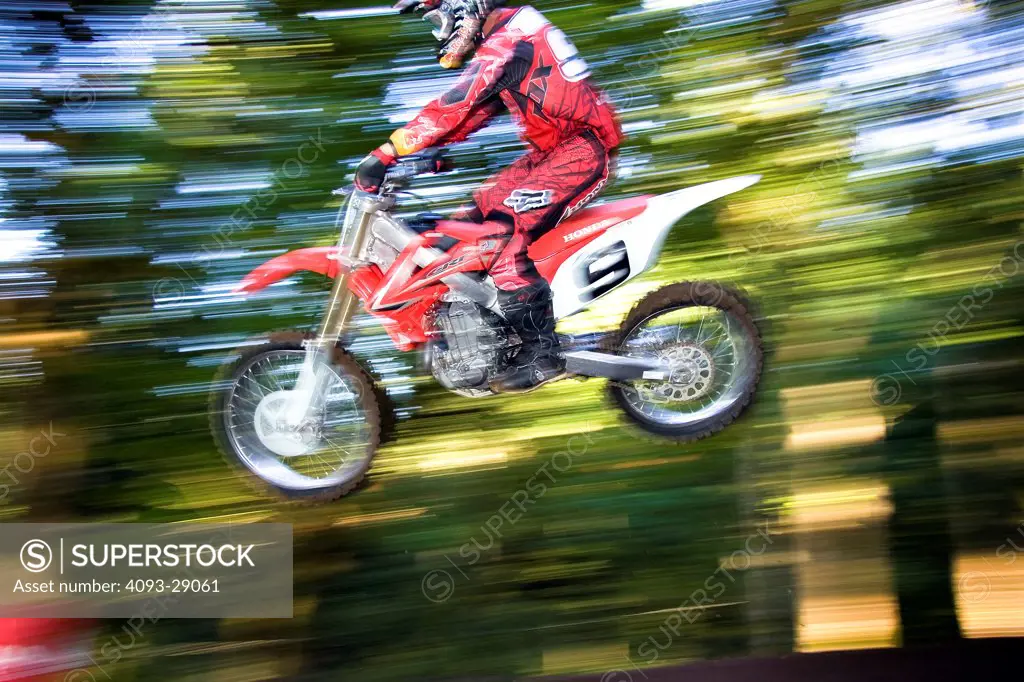 2008 Honda CRF 450R with rider Ivan Tedesco on dirt track course in forest, leaping action, side view