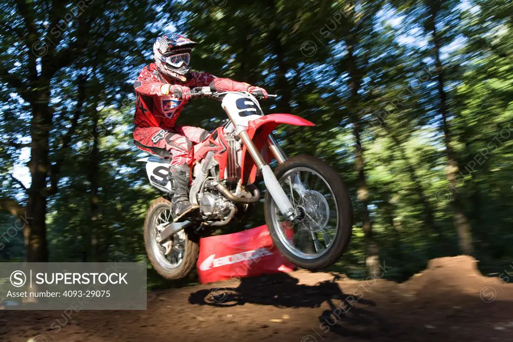 2008 Honda CRF 450R with rider Ivan Tedesco on dirt track course in forest, leaping action front 3/4