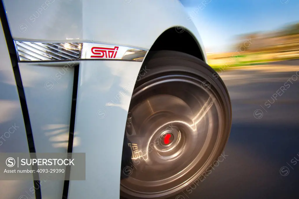 Exterior action detail view of a white 2012 Subaru Impreza WRX STI showing the badge logo and wheel tire rim.