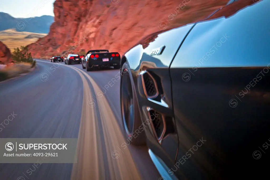 Action of several 2013 Chevrolet Corvette ZR-1 on a rural, desert mountain road.