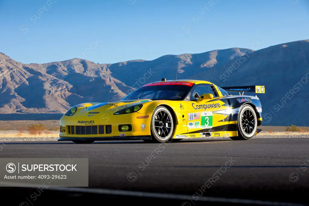Front 3/4 static of a yellow 2013 Chevrolet Corvette ZR-1 race car parked on a desert road.