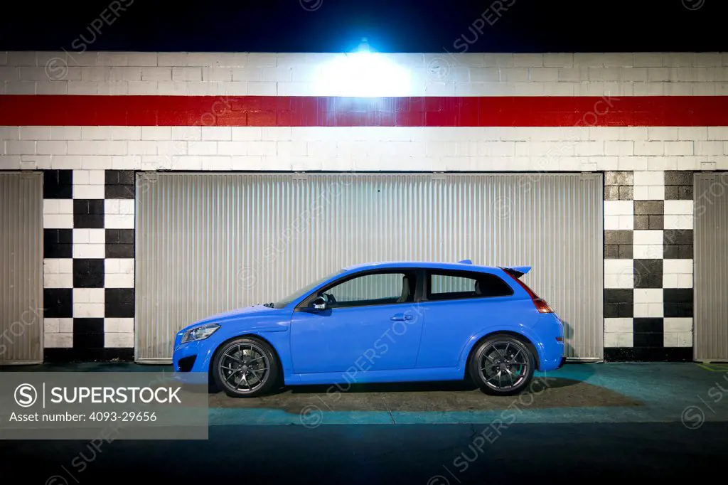 Profile static of a blue 2013 Volvo C30 T5 Polestar parked next to a garage.