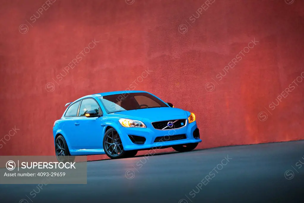 Front 3/4 static view of a blue 2013 Volvo C30 T5 Polestar parked next to an orange wall.