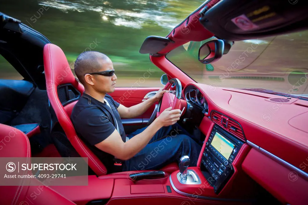 Interior action of a man driving a silver 2013 Ruf RT Roadster with a bright red leather interior.