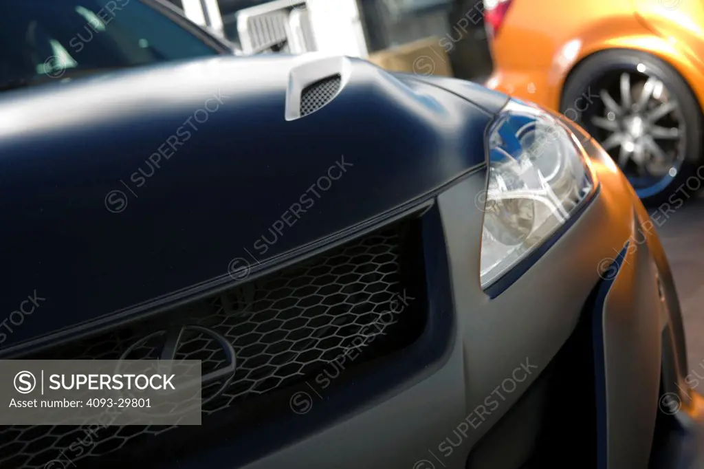 Detail view of a highly modified matte black 2012 Lexus IS-F at the SEMA Auto Show. Showing the grill and headlight.