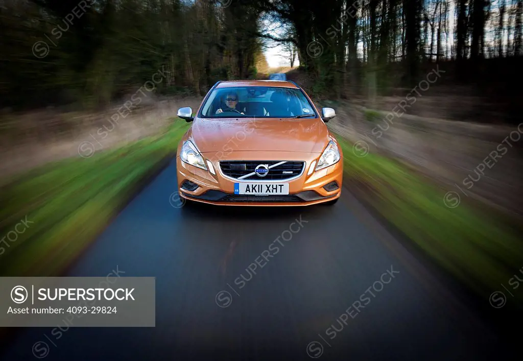 Straight on nose action of a 2013 Volvo V60 wagon with DRIVe diesel engine on a rural tree lined road in England