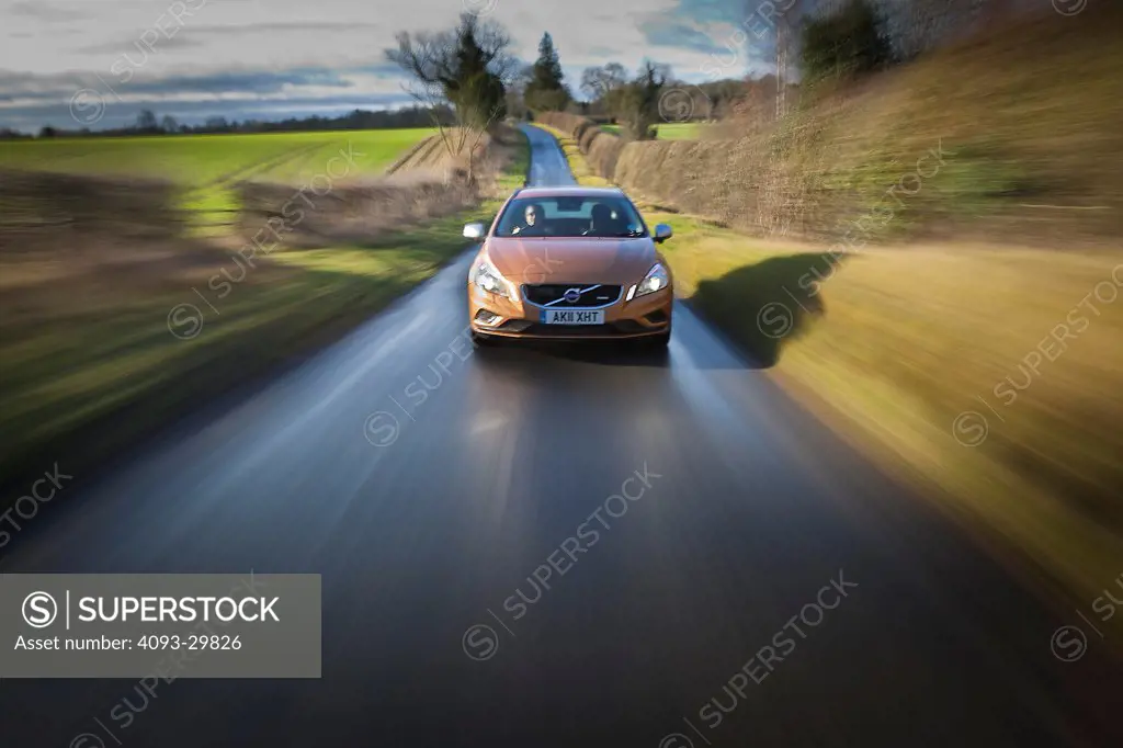 Straight on nose action of a 2013 Volvo V60 wagon with DRIVe diesel engine on a rural tree lined road in England
