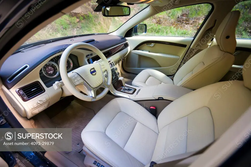 Interior of a 2013 Volvo XC70 showing the steering wheel, instrument panel, center console, dashboard and tan leather seats.