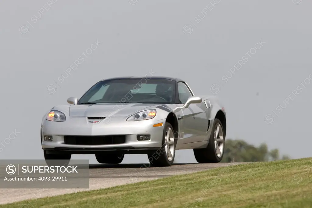 2010 Chevrolet Corvette Grand Sport driving on a race track, front 3/4 action view