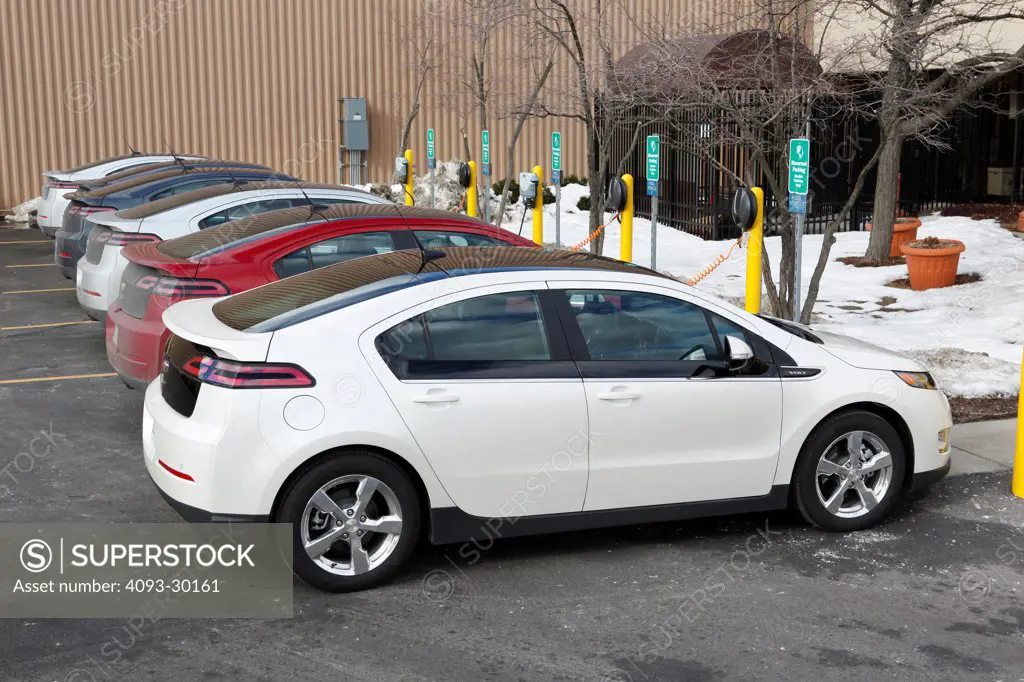 Row of 2012 Chevrolet Volt gas electric hybrids parked at a charging station in winter.