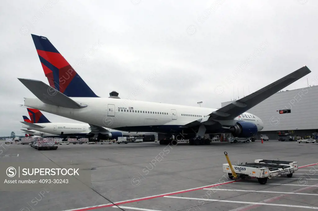Rear 3/4 view of a 2012 Delta Airlines Boeing 777-232/ER parked on the ramp or tarmac at an airport gate.