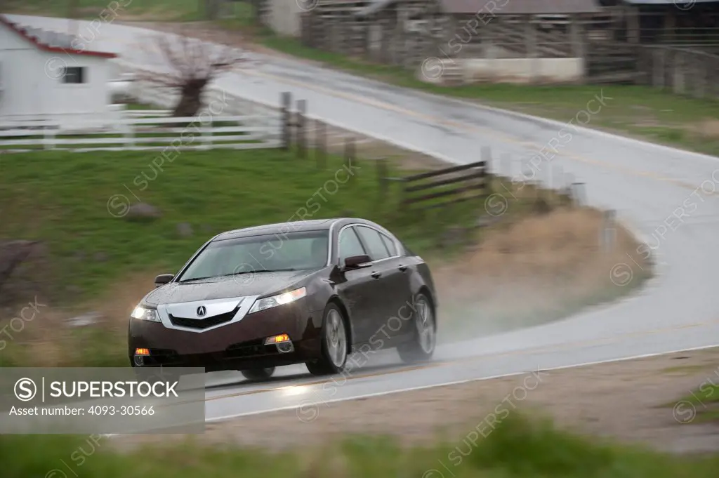 2011 Red Acura TL SH-AWD driving on a rural mountain road in the rain, front 3/4 action view