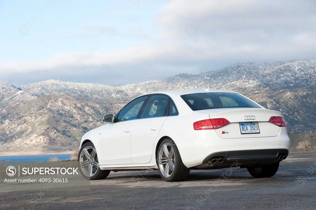 2011 White Audi S4 parked on a desert road with mountains in the background, rear 3/4 static view