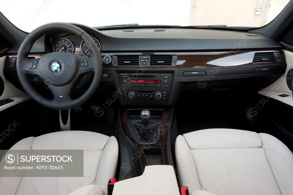 2011 Blue BMW 335i interior showing the steering wheel, instrument panel, center console, manual six speed gear shift lever and white leather seats