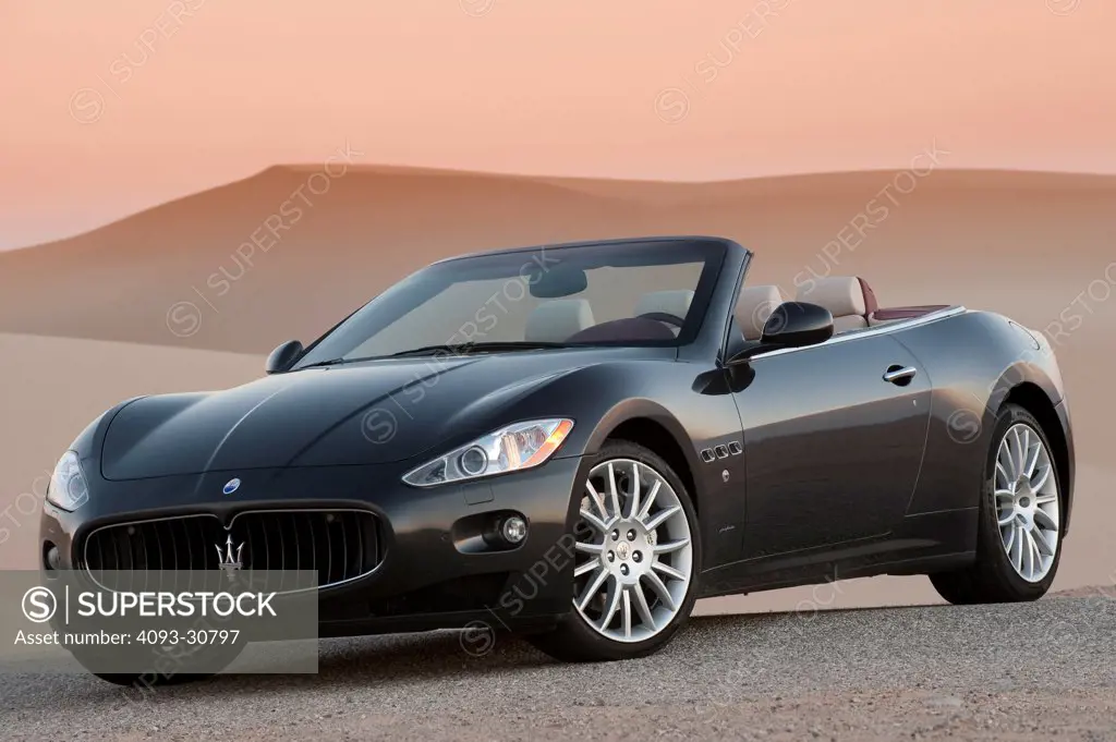 2011 Maserati GranCabrio parked next to sand dunes at dusk, front 3/4 static view
