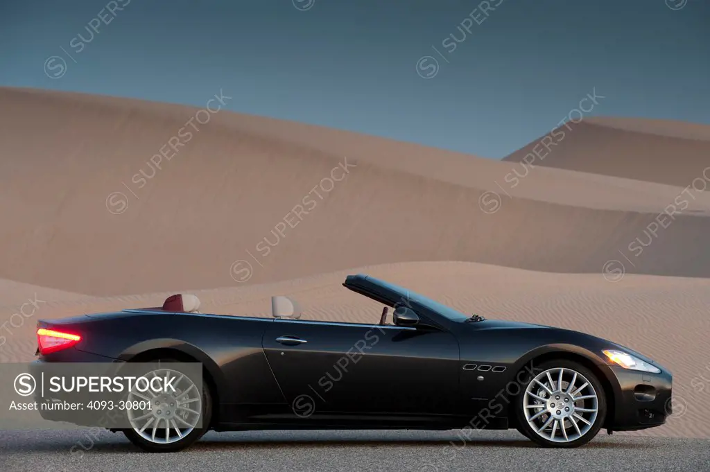 2011 Maserati GranCabrio parked next to sand dunes at dusk, profile static view