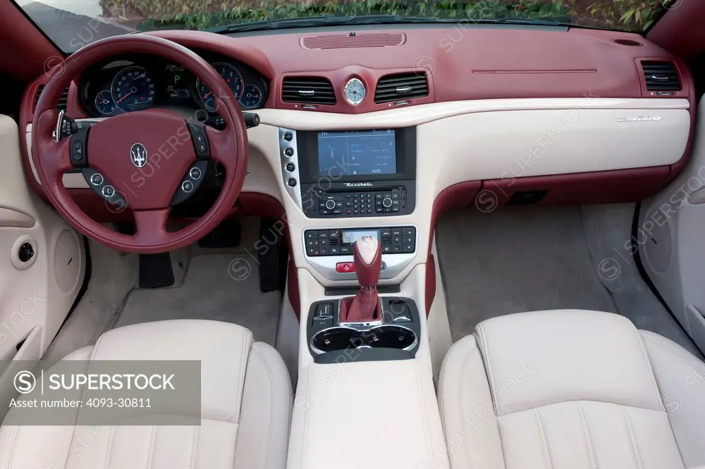 2011 Black Maserati GranCabrio with the top down showing the steering wheel, instrument panel, dashboard, center console, gear shift lever and white leather seats, interior view