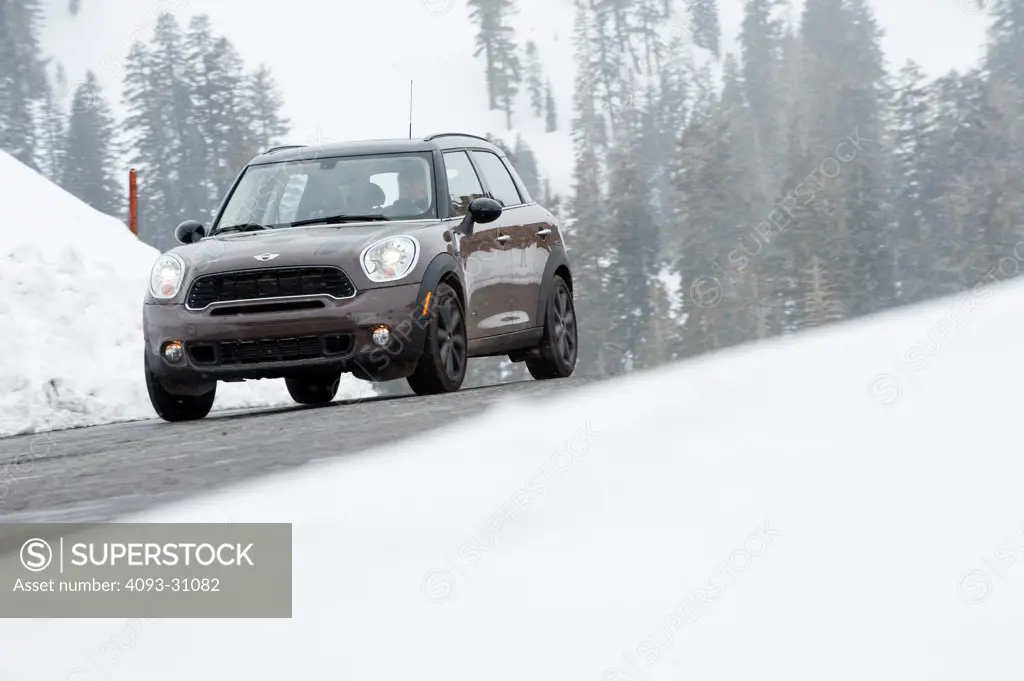 Front 3/4 view of a 2011 Mini Countryman driving on a snowy road.