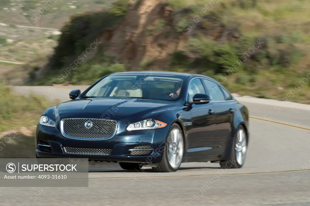 Front 3/4 view of a 2012 Jaguar XJL driving on a mountain road.
