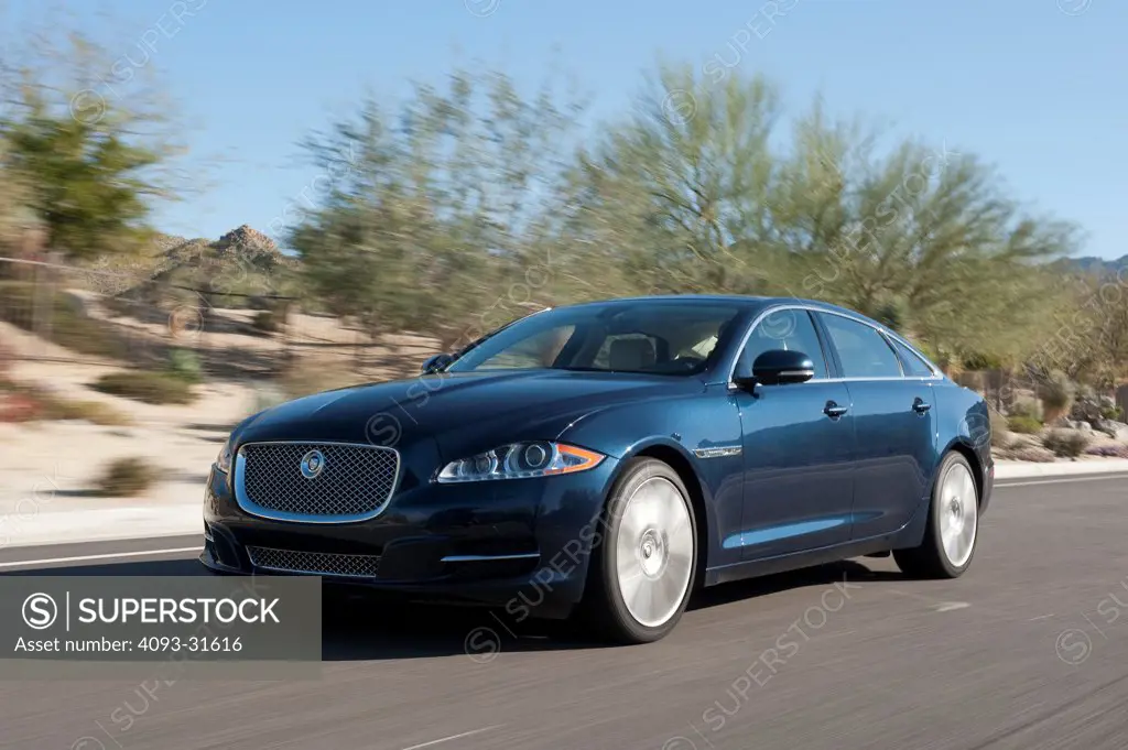 Front 3/4 view of a 2012 Jaguar XJL driving on a rural desert road.