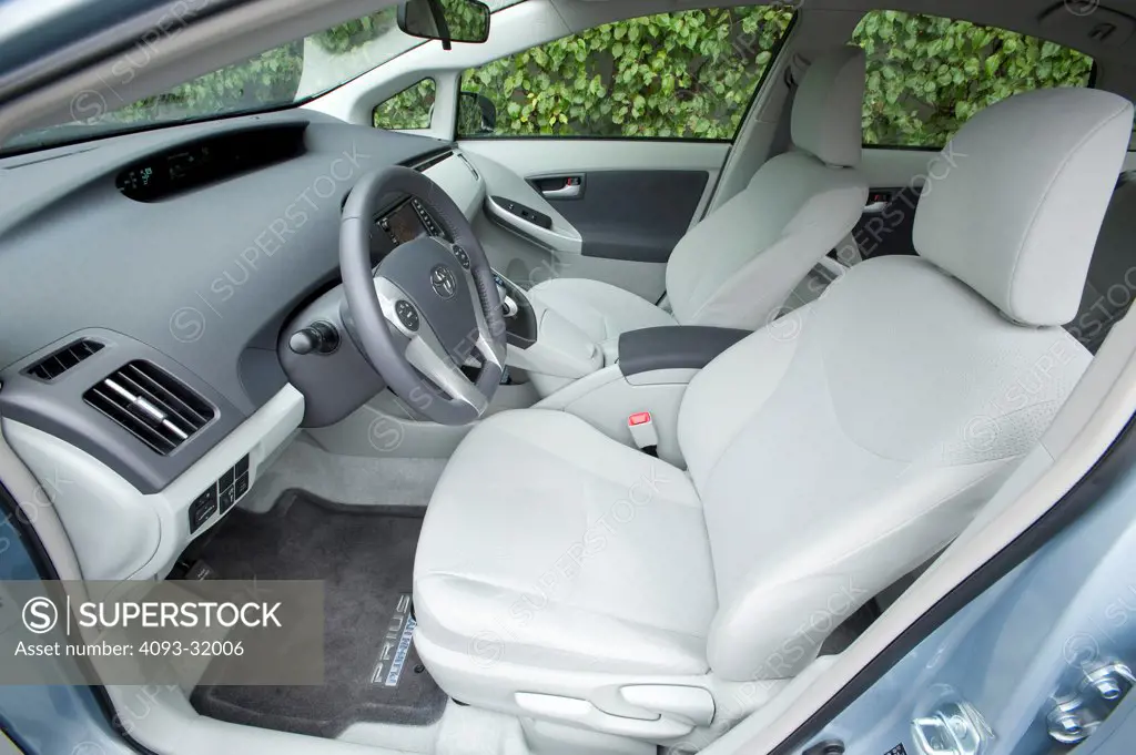 Driver's side view of the interior of a 2012 Toyota Plug-In Prius showing the dash, steering wheel and seats.