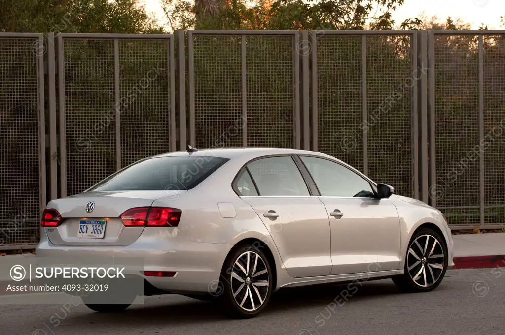 Rear 3/4 view of a silver 2012 Volkswagen Jetta GLI parked in a parking lot near a rural area.
