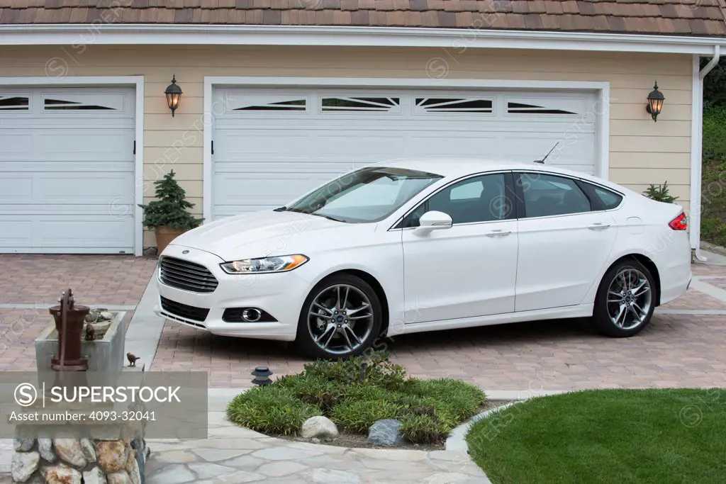 Front 7/8 view of a white 2013 Ford Fusion Titanium parked in front of a house in a suburban neighborhood.