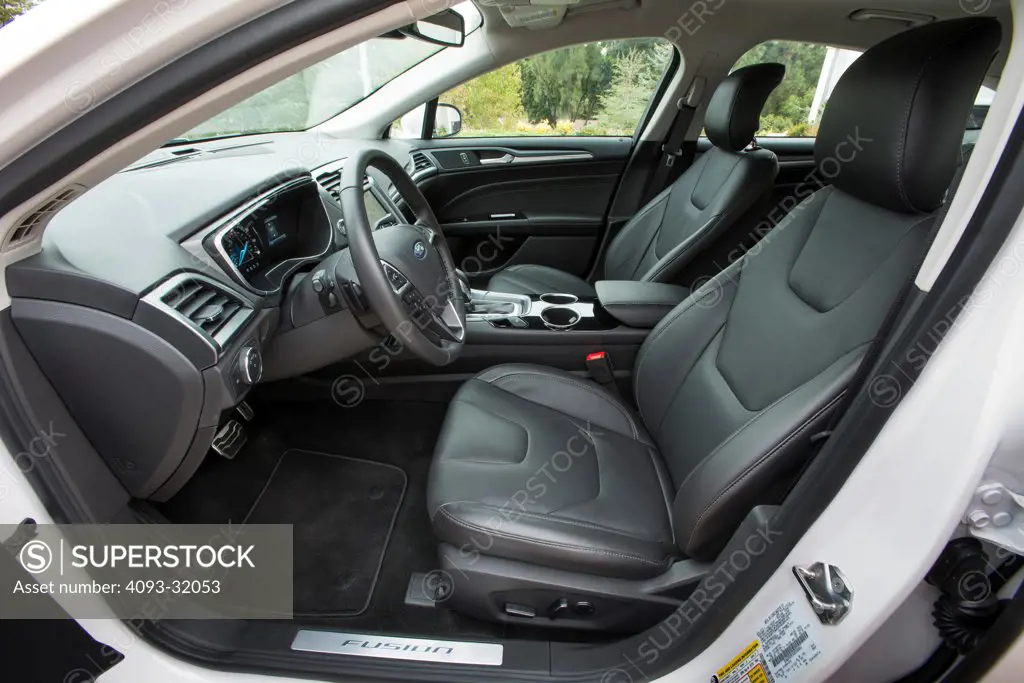 Driver's side view of the interior of a 2013 Ford Fusion Titanium showing the dashboard, steering wheel and seats.