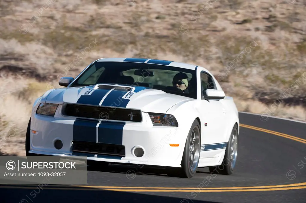 Front 3/4 view of a 2011 Ford Mustang Shelby GT350 45th Anniversary Edition driving on a rural desert road.