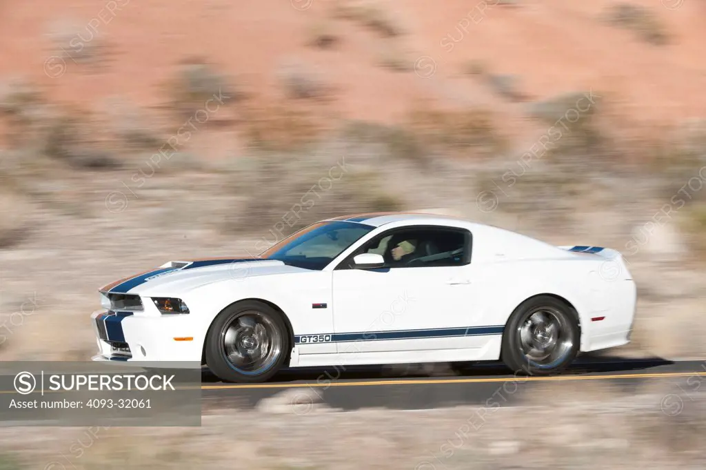 Profile view of a 2011 Ford Mustang Shelby GT350 45th Anniversary Edition driving on a rural desert road.