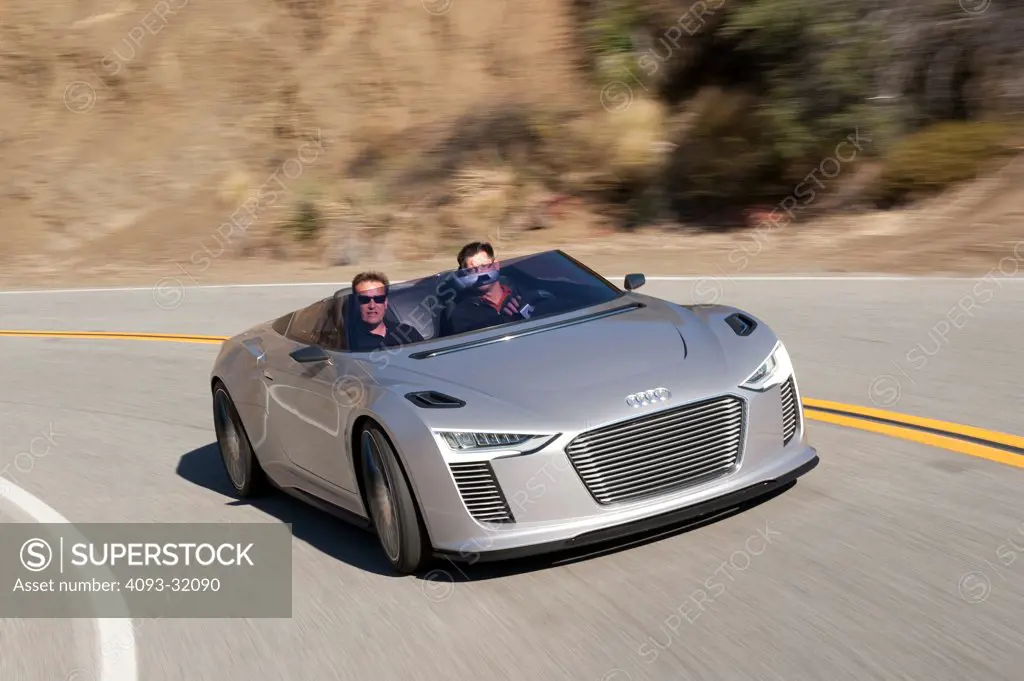 Front 3/4 view of a convertible silver Audi e-tron Spyder Concept driving on a rural desert road.