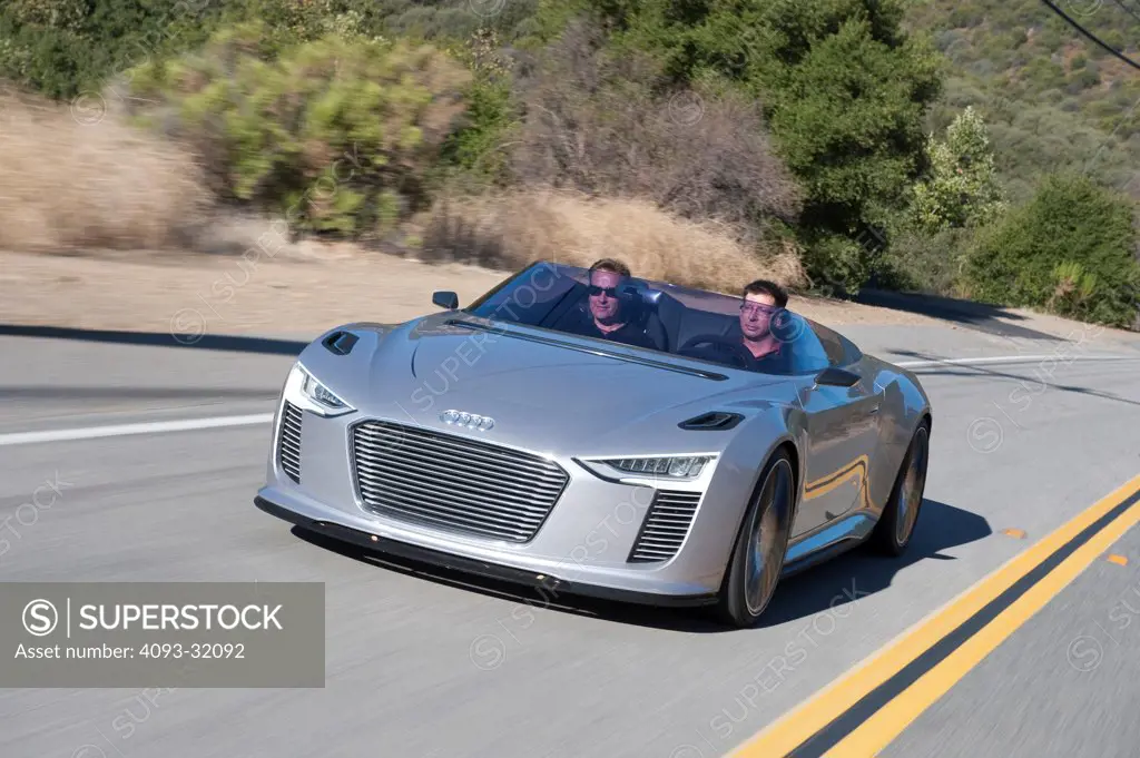 Front 3/4 view of a convertible silver Audi e-tron Spyder Concept driving on a rural mountain road.