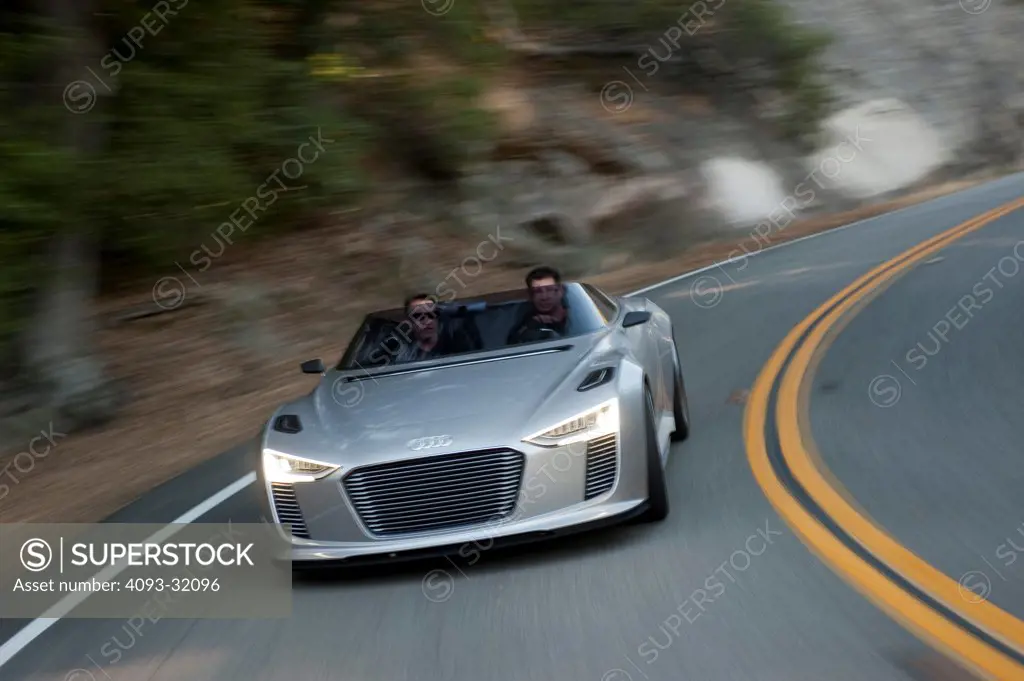 Front view of a convertible silver Audi e-tron Spyder Concept driving on a rural mountain road.