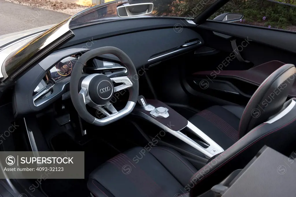 Driver's side view of the interior of an Audi e-tron Spyder Concept with the door open, showing the dashboard, steering wheel and seats.