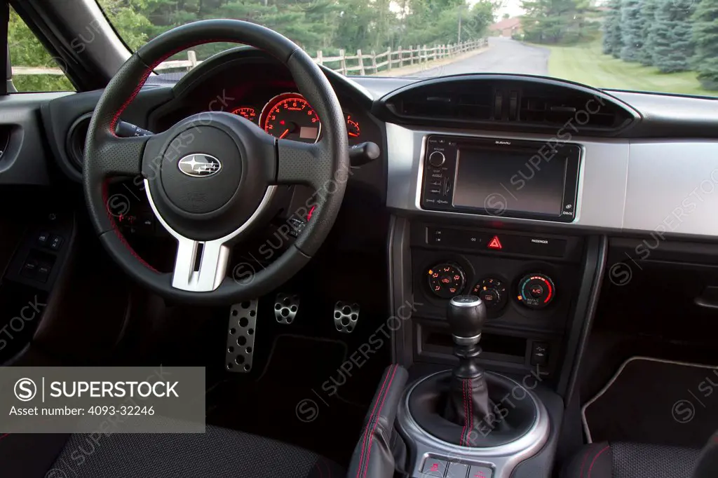 Interior view of a 2013 Subaru BRZ showing the steering wheel, shifter and dashboard.