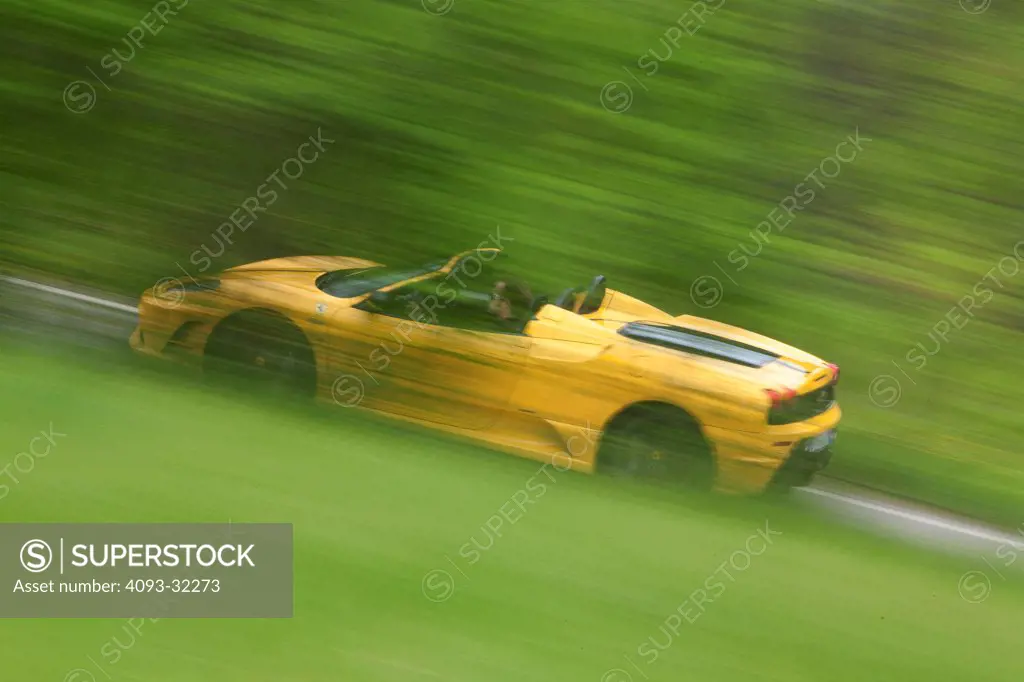 2009 Ferrari F430 Scuderia Spider speeding along road, side view