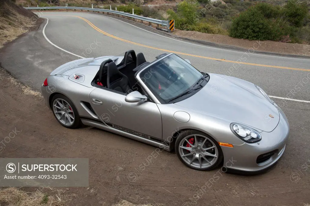 Front 3/4 static view of a silver 2012 Porsche Boxster Spyder parked on the side of a rural mountain road.