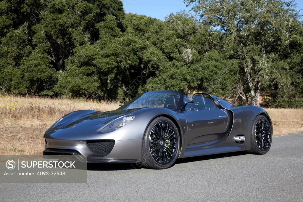 Front 3/4 static view of a 2012 Porsche 918 Spyder Hybrid concept parked on a rural mountain road.