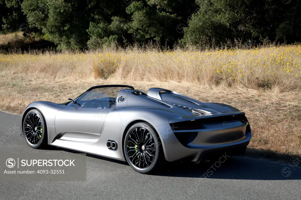 Rear 3/4 static view of a 2012 Porsche 918 Spyder Hybrid concept parked on a rural mountain road.