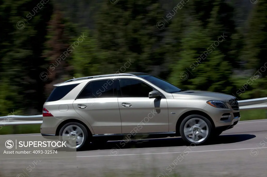 Profile action of a silver 2012 Mercedes-Benz ML350 on a rural mountain road.