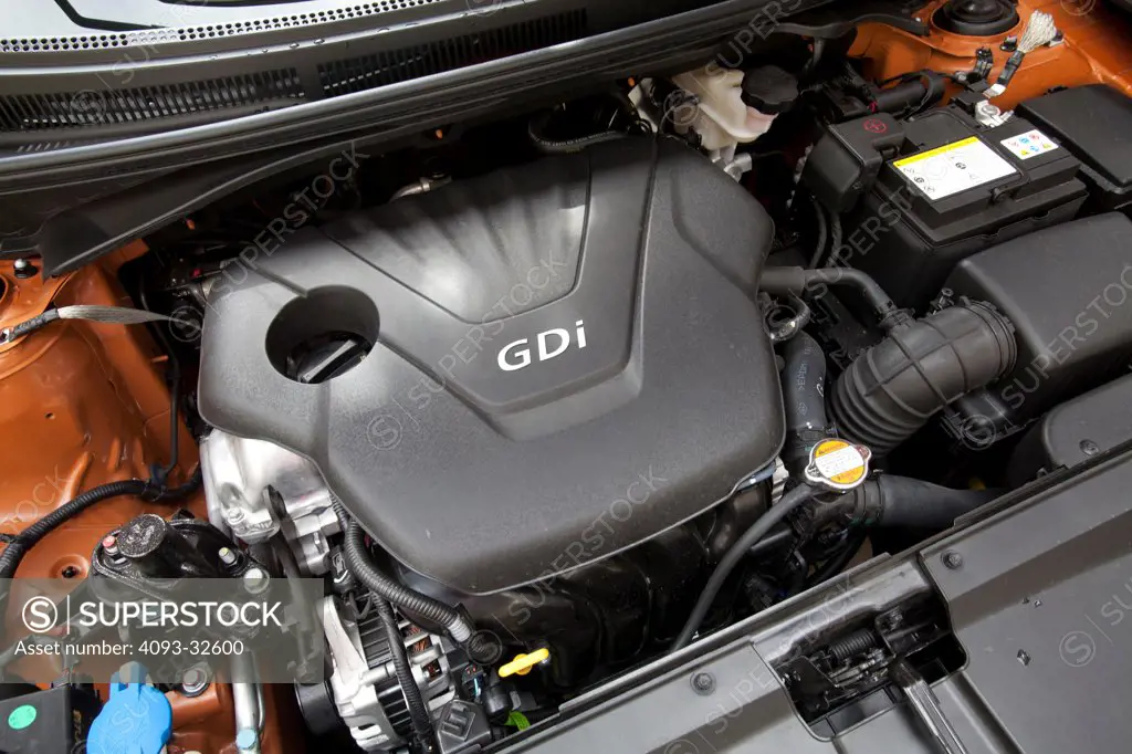 Engine view of an orange 2012 Hyundai Veloster showing the 1.6 liter GDi motor.