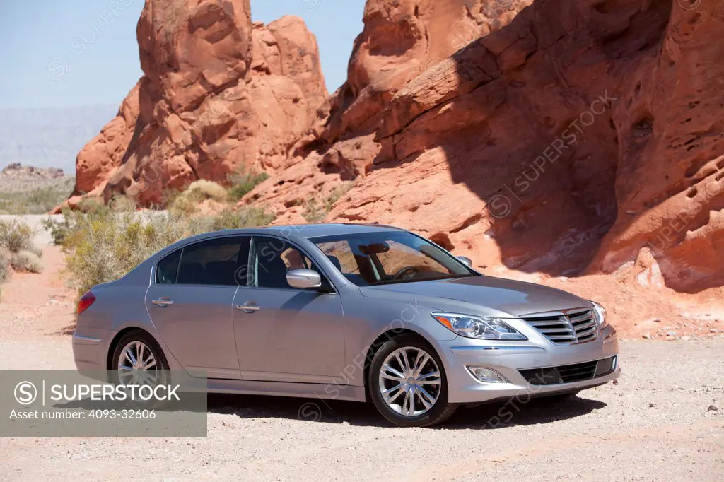 Front 3/4 static of a silver 2012 Hyundai Genesis R-Spec parked on gravel in a rural desert area with red rocks in the background.