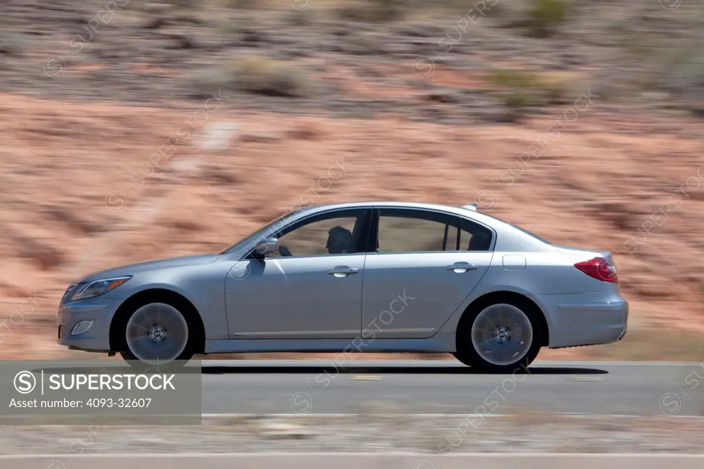 Profile action of a silver 2012 Hyundai Genesis R-Spec on a rural, desert, mountain road.