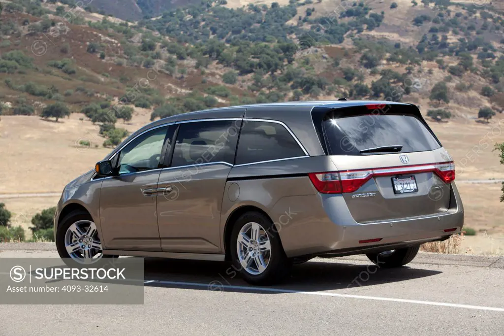 Rear 3/4 static view of a 2012 Honda Odyssey parked on the side of a rural mountain road.