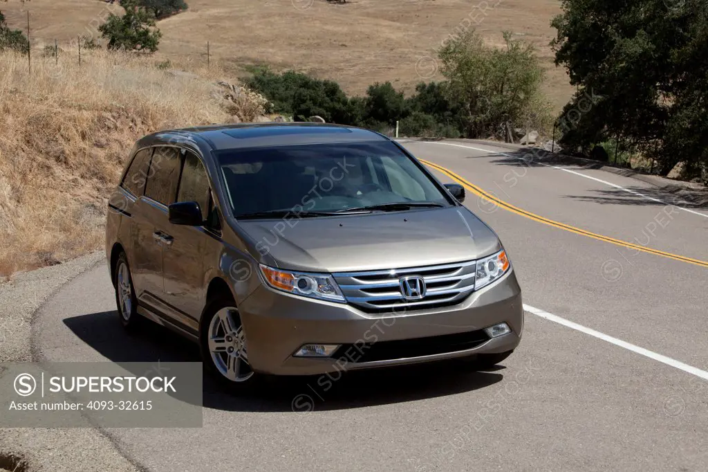 Front 3/4 static view of a 2012 Honda Odyssey parked on the side of a rural mountain road.