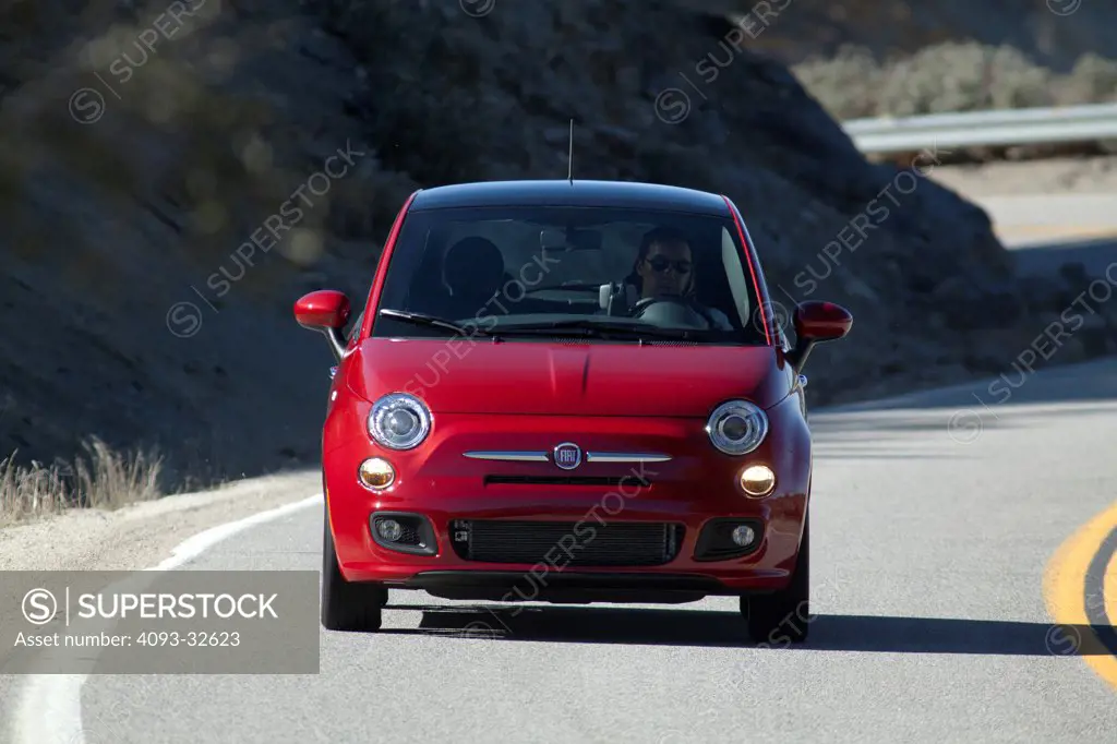 Straight on nose action of a red 2012 Fiat 500 cornering on a rural mountain road.