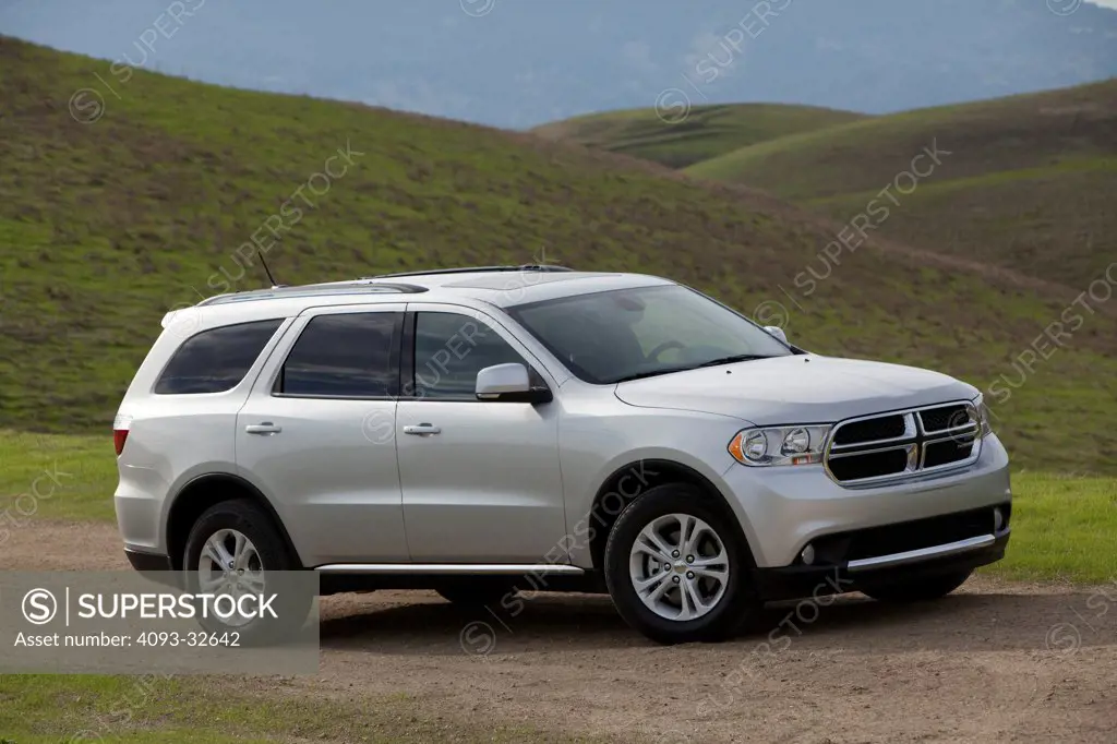 Front 3/4 static view of a silver 2012 Dodge Durango parked on a rural gravel dirt mountain road.