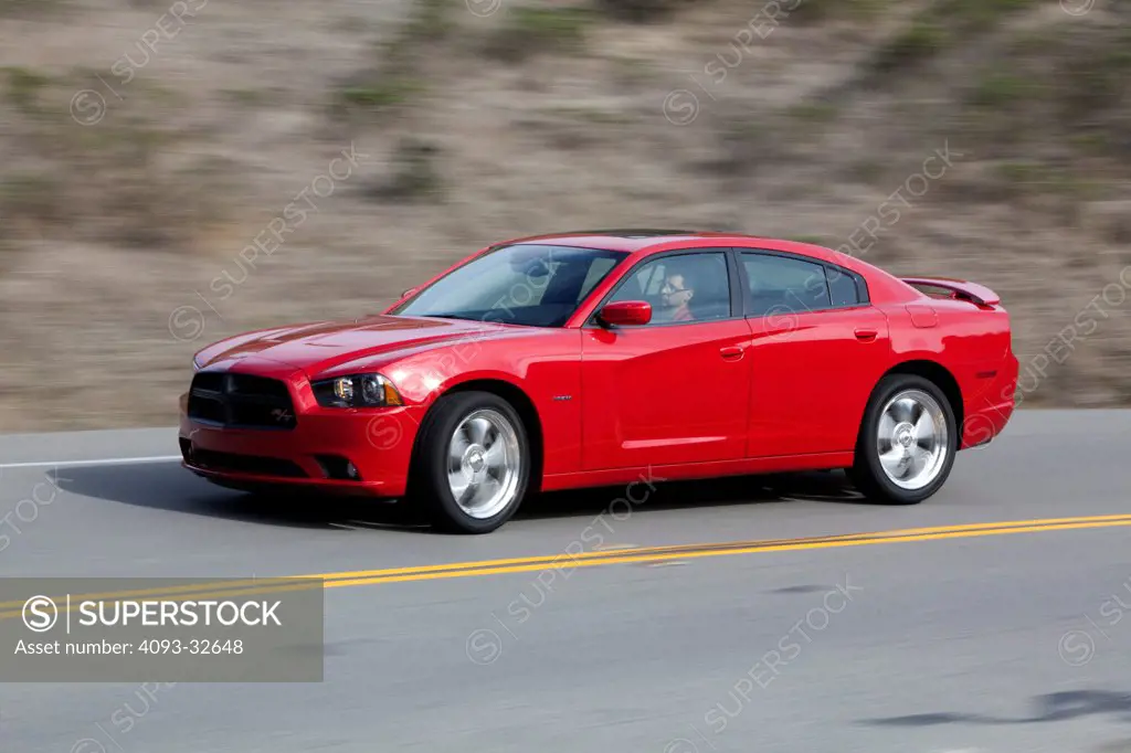Front 3/4 action of a red 2012 Dodge Charger R/T HEMI on a rural mountain road.