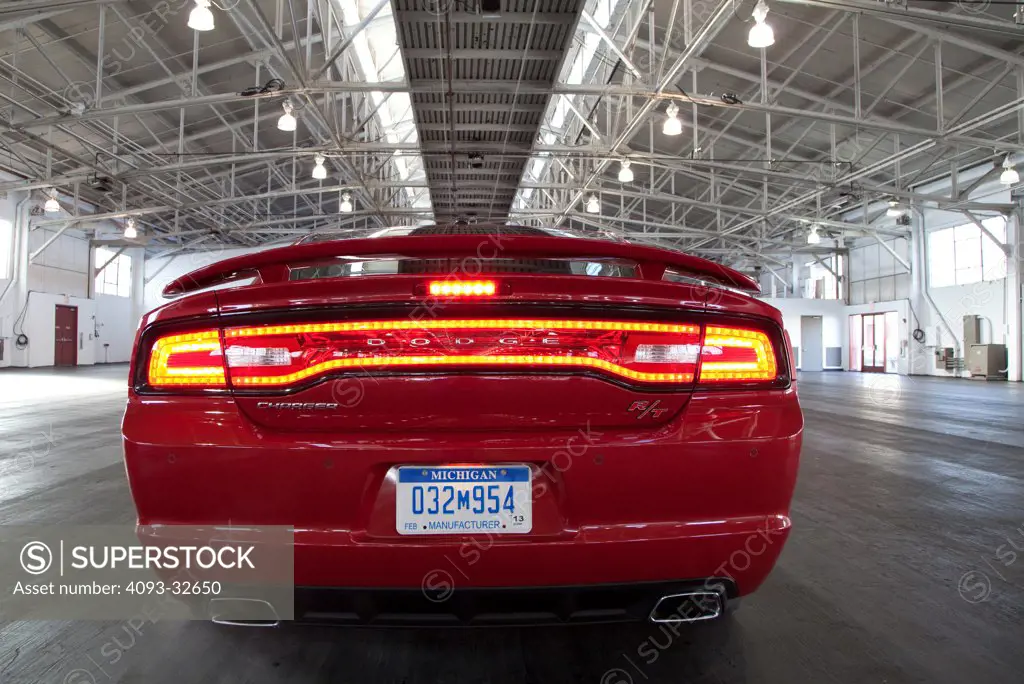 Straight on rear static view of a red 2012 Dodge Charger R/T HEMI parked inside a warehouse.