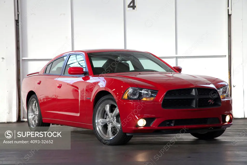 Front 3/4 static view of a red 2012 Dodge Charger R/T HEMI parked inside a warehouse.